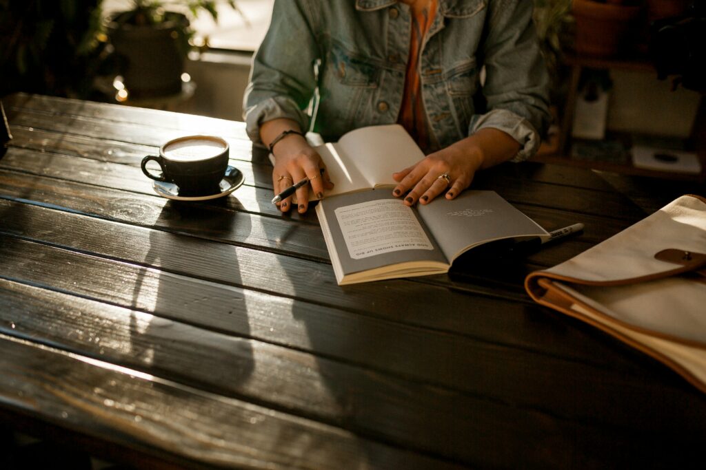 Woman at a planked table writing and enjoying a coffee